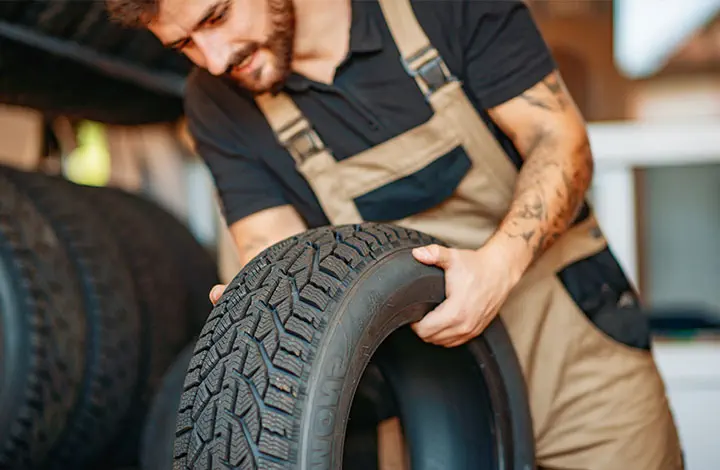 Employé du service de pneus avec des pneus de voiture